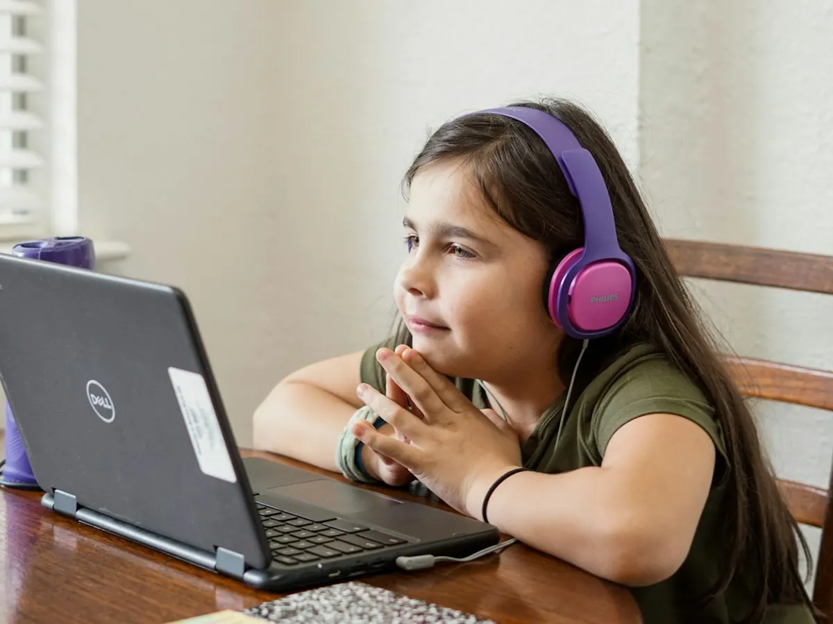 A girl wearing headphones following a lesson on her laptop