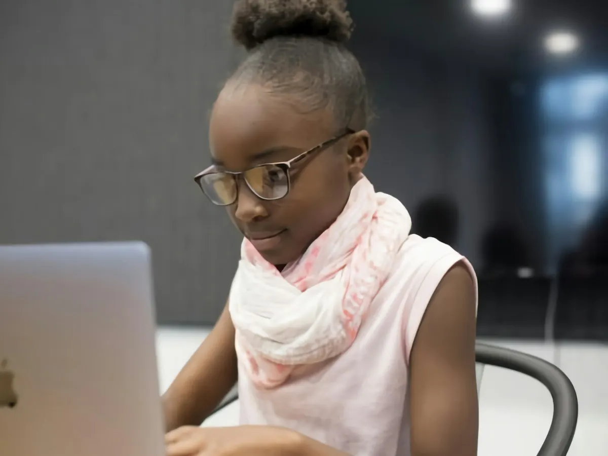 A girl in glasses concentrating on a coding lesson on her laptop