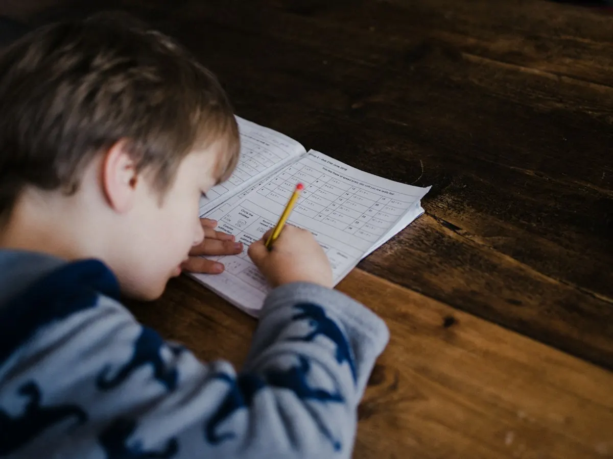 A primary school boy working through maths problems in an exercise book