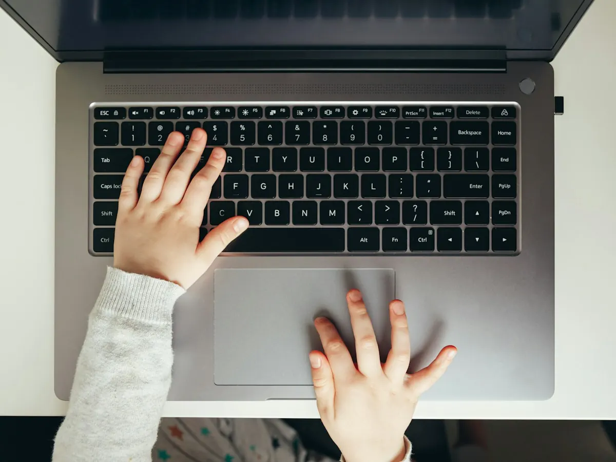 A child’s hands typing on a laptop keyboard