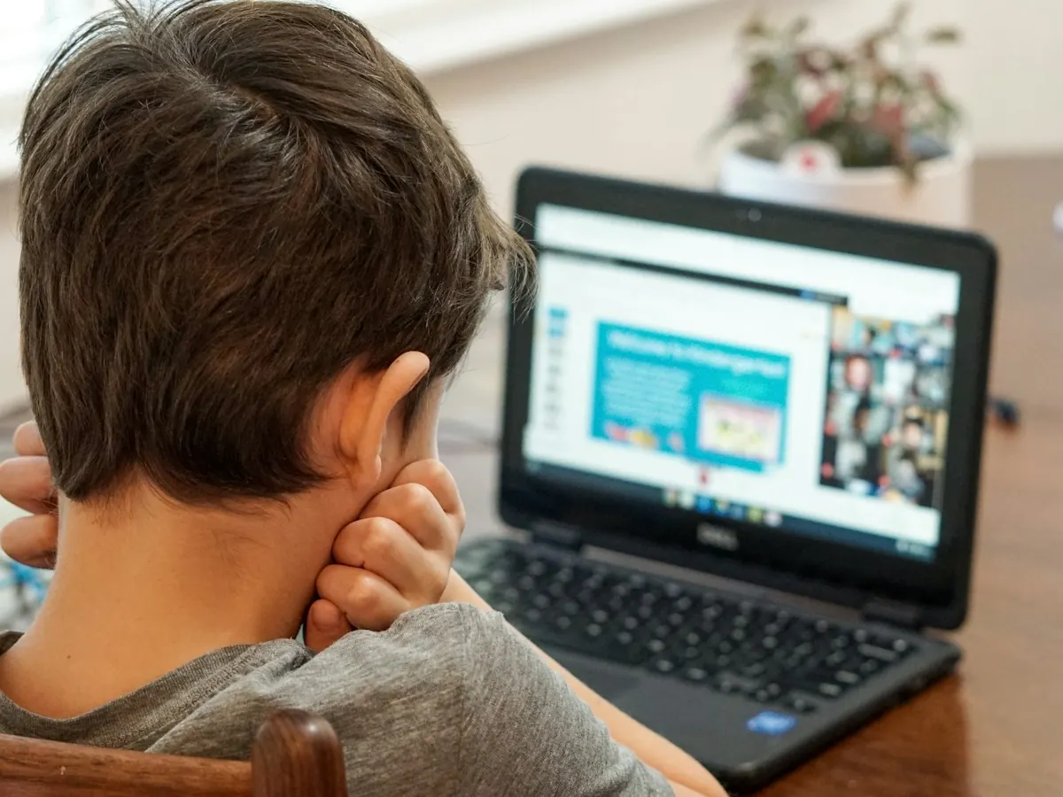 A young boy following an online lesson on a laptop